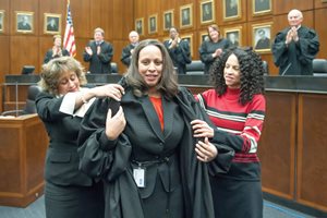 U.S. District Judge Andrea R. Wood gets an assist from her sisters, Angela Winston (left) and Anita Wood, and a standing ovation from her fellow judges during the special ceremonial session for her induction, investiture and installation in the ceremonial courtroom of the Dirksen Federal Courthouse. 